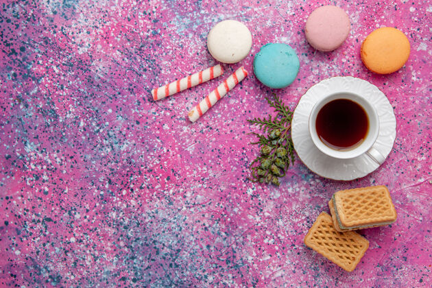 糖顶视图一杯茶 配上五颜六色的法国马卡龙和华夫饼 粉色墙壁蛋糕饼干糖甜饼茶装饰麦卡龙五颜六色
