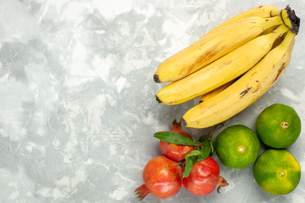 维生素在浅白色的桌子上俯瞰新鲜的黄色香蕉和石榴和橘子番茄顶级蔬菜
