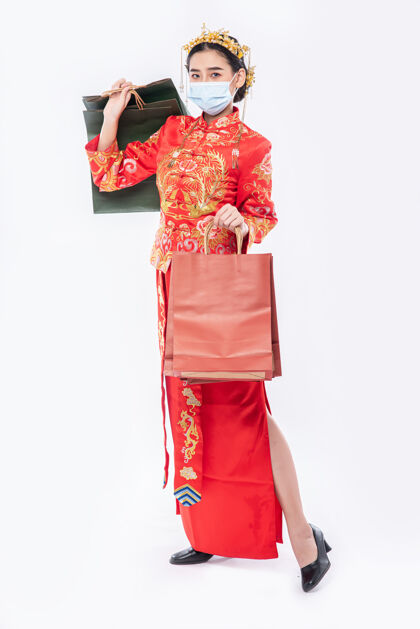 女孩女人穿着旗袍 戴着口罩 拿着纸袋在中国新年购物面具购物庆祝