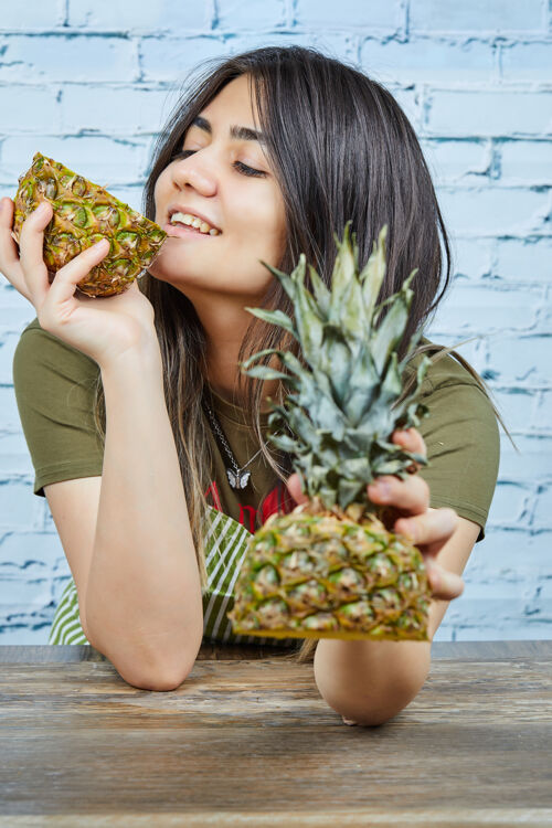 水果快乐的年轻女子拿着菠萝在蓝色的表面有机一半Ananas