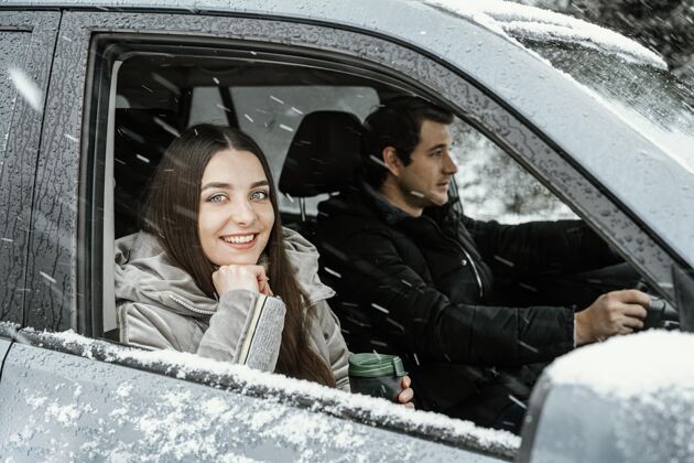 女性侧视图笑脸夫妇在车上 而在公路旅行冒险冬天户外