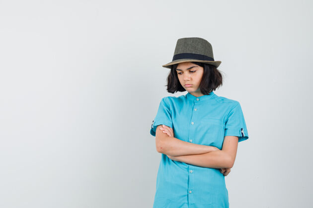 蓝色穿着蓝色衬衫 戴着帽子 双臂交叉站着的年轻女士看起来很生气女人时尚黑发