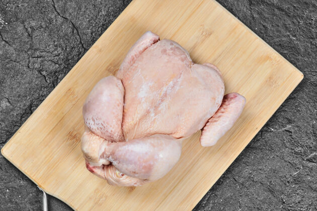 杂货店生的整只鸡放在木砧板上家禽鸡排骨
