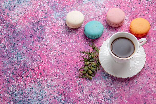 顶部顶视图：一杯茶 配上五颜六色的法国马卡龙 粉色的蛋糕 饼干 甜甜的馅饼茶新鲜鲜花