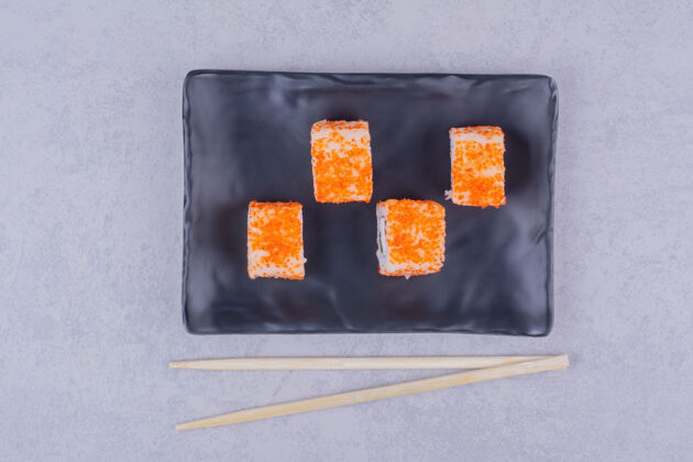 菜肴黑色陶瓷盘中的鲑鱼寿司卷质量产品简约