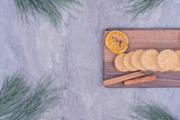 极简用肉桂棒和干柠檬片放在木板上的饼干圣诞节地壳烹饪