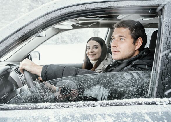 逗留一对夫妇在公路旅行时在车里的侧视图探索男人冬天
