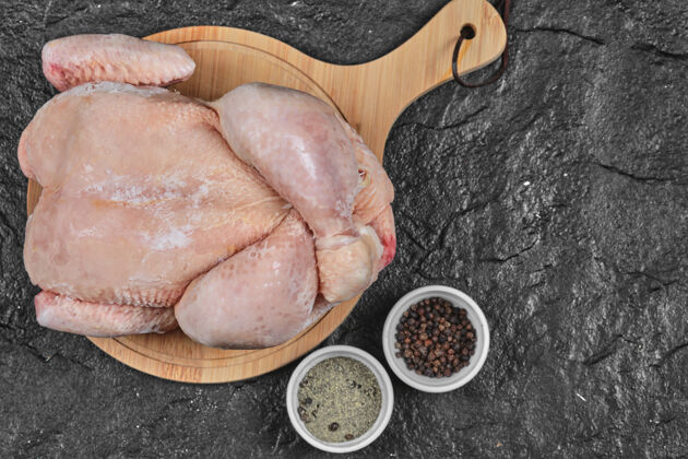 新鲜生的整只鸡放在木板上加香料肉鸡板有机