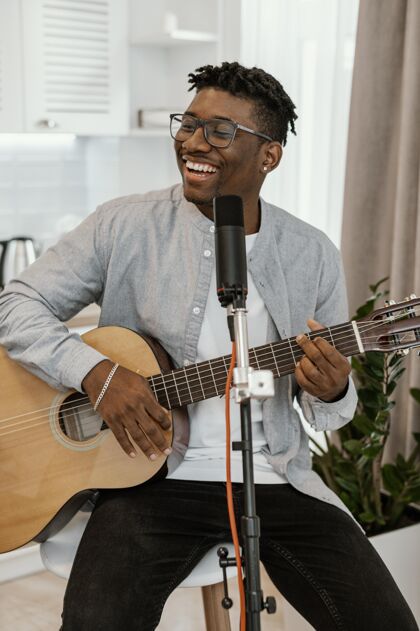 垂直笑脸男音乐家在家弹吉他唱歌的正面图音乐家乐器人才