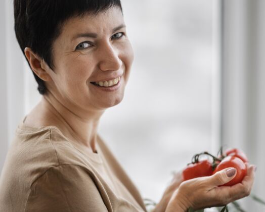 女人笑脸女人抱着自家种的西红柿的侧视图园艺草药女人