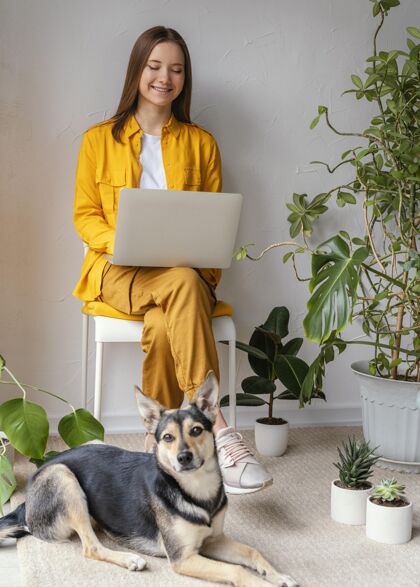 室内在自家花园里工作的年轻女人 就在她的狗旁边狗栽培生态室内