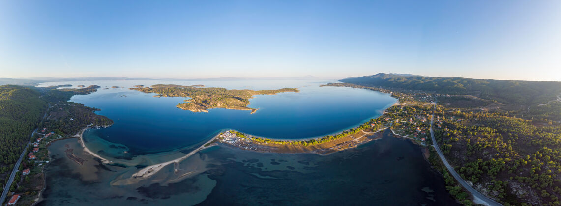 岩石爱琴海海岸的广角镜头 海岸和岛屿上有一座城镇 蓝色透明的海水 周围绿意盎然 从无人机俯瞰帕莫拉马 希腊海度假村沙