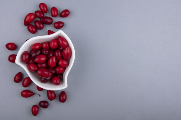 空白白色碗上新鲜多汁的红色山茱萸浆果的顶视图 背景为灰色 有复印空间碗状新鲜灰色