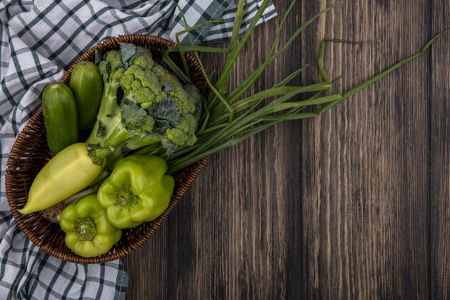蔬菜顶视图黄瓜与青椒花椰菜和葱在篮子里的木制背景顶部新鲜食物