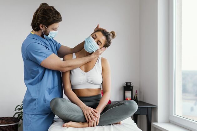 女人男性骨科治疗师带着医用面罩检查女性患者的颈部肌肉女人医生男人