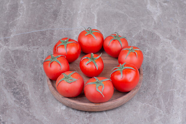 季节红色的西红柿放在大理石上的木盘里热带水果异国情调