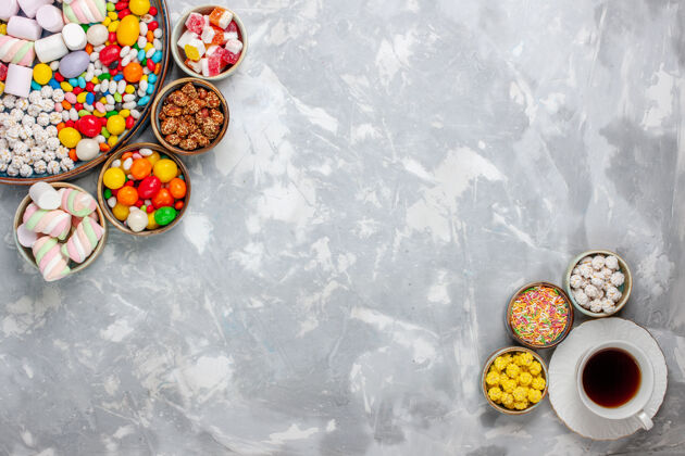 视图顶视图糖果组成不同颜色的糖果与棉花糖和茶在白色的办公桌上糖果邦邦甜封糖果生的合成