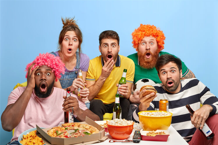 多样性五个不同的朋友震惊地盯着电视机零食比赛友谊