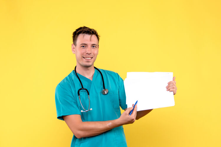 前面黄色墙上拿着文件的男医生的正视图制服诊所男医生
