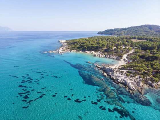 海滩爱琴海沿岸有蓝色透明的海水 周围绿树成荫 岩石 灌木丛和树木 从无人驾驶飞机上俯瞰希腊山镁砂海