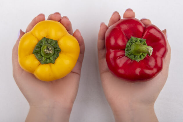 手俯视图白色背景上手持黄色和红色彩色甜椒的女人胡椒黄食物
