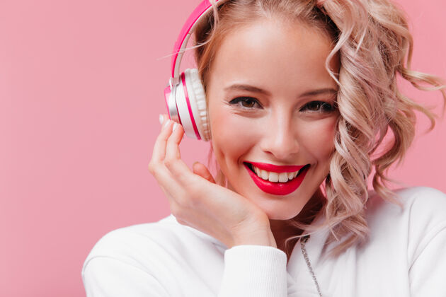模特年轻女子摆姿势 通过她的粉红色耳机听音乐肖像放松服装