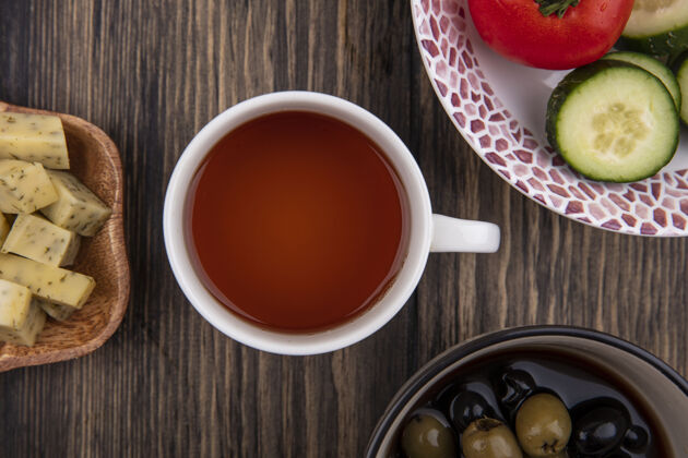 杯子一杯茶的顶视图 在木制背景上放着橄榄 蔬菜和切碎的奶酪片切片饮料桌子