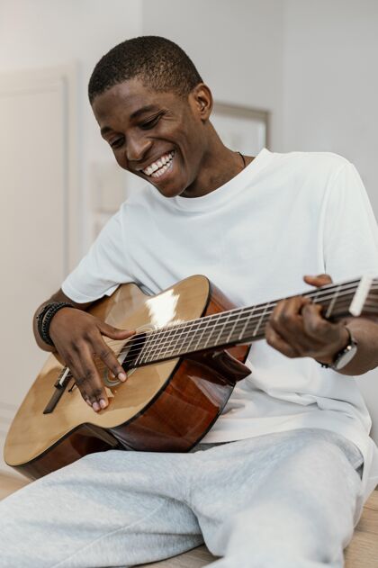 乐器笑脸男音乐家在家弹吉他的正面图创意男性男人