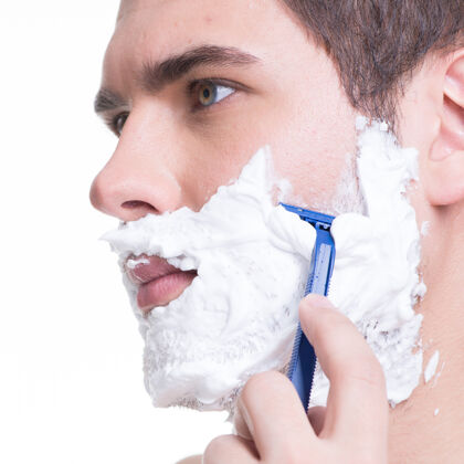 浴室年轻人用剃刀刮胡子肖像帅哥男人