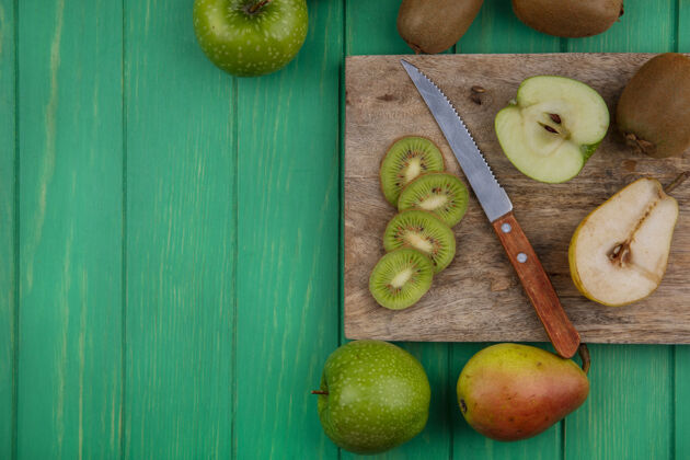 猕猴桃顶视图猕猴桃片在一个立场上与一把刀绿色的苹果和梨在一个绿色的背景绿色苹果支架