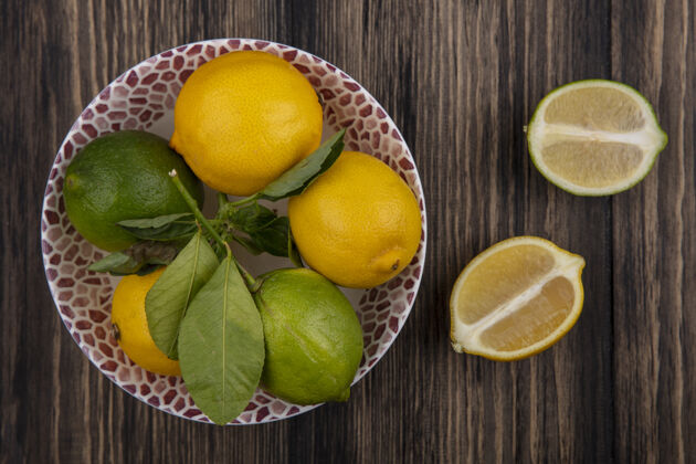 新鲜顶视图柠檬与柠檬在一个板与楔形木背景盘子水果柠檬