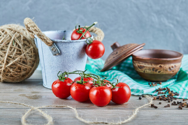 串一桶西红柿和丁香放在空碗的木桌上木材湿食物