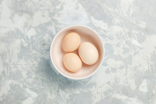 整个顶视图生全蛋在浅白桌子上的小盘子里生食早餐照片早晨视图鸡蛋顶部