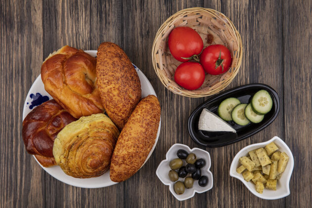 橄榄顶视图面包盘上新鲜的西红柿桶上橄榄碗上的木制背景盘子面包食物
