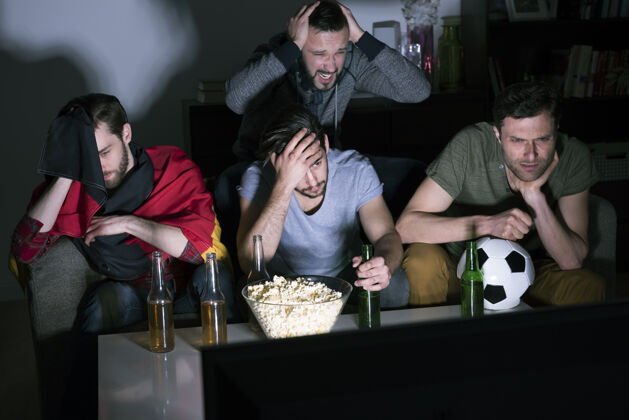 友谊一群男人在电视上喝啤酒看足球电视难以置信啤酒瓶