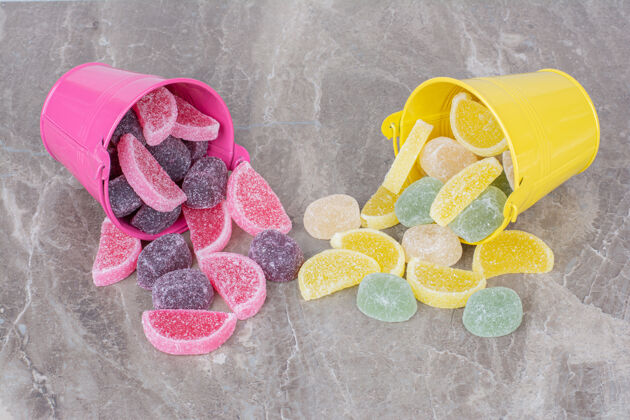 粉色黄色和粉色的桶 大理石背景上有糖果酱桶糖果可口