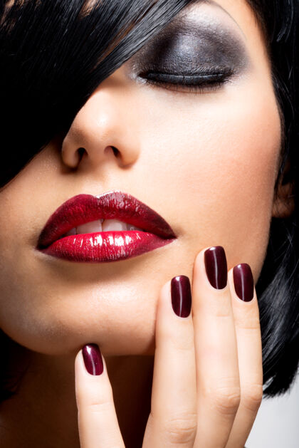 嘴唇一张长着漂亮黑指甲和性感红唇的女人的脸一头黑发的时尚模特华丽直发指甲