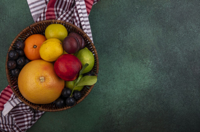 绿色顶视图复制空间葡萄柚与柠檬 桃子 樱桃 李子 橘子和李子在一个绿色的背景篮子里视野樱桃李子