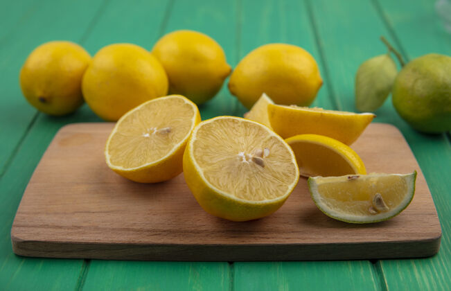 酸橙前视图绿色背景上的砧板上柠檬与石灰楔五颜六色食物楔形