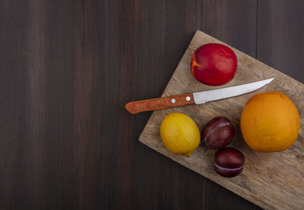 柑橘顶视图复制空间柠檬与橙色和桃子与李子在砧板上与刀木背景木头顶空间