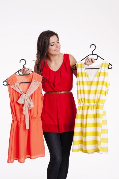 零售女人在橙色和条纹连衣裙之间选择站穿衣服女性