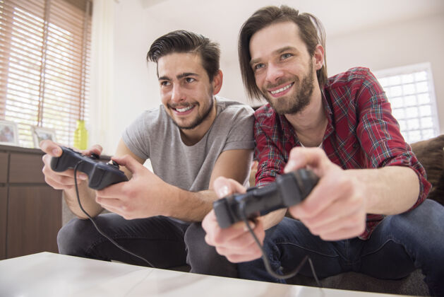 房子玩电子游戏的朋友们享受举行牙齿微笑