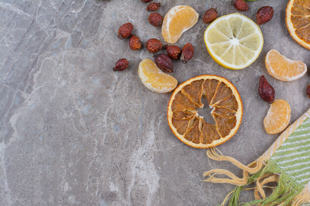水果石头背景上有柑橘类水果片和玫瑰果玫瑰果美味柠檬