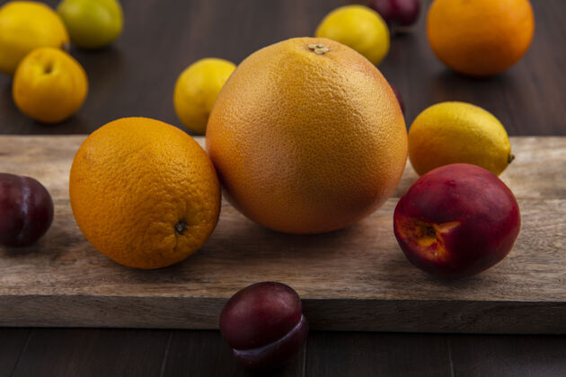 橘子前视图李与葡萄柚柠檬橙和桃子砧板上的木制背景桃子李子切