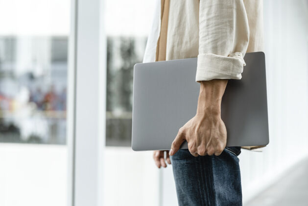 时尚一个在城里散步的人拿着他的笔记本电脑亚洲企业家程序