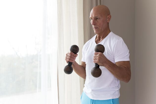 锻炼高级男子使用健身哑铃健康健身运动员