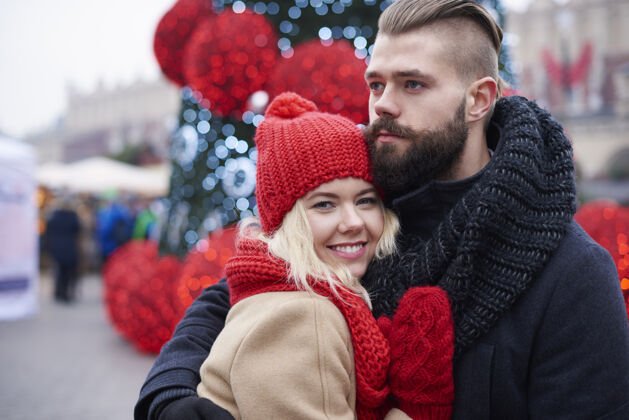 站着圣诞期间的年轻夫妇围巾节日城市生活