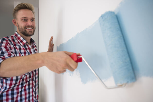 家居装修年轻人在画蓝色的墙装修室内工作