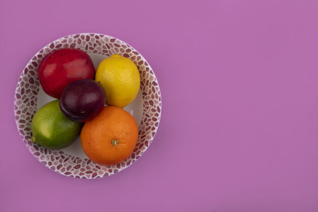 复制顶视图复制空间柠檬与石灰桃李和橙色在一个盘子上粉红色的背景空间新鲜橘子