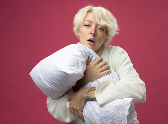 拥抱生病的不健康的女人 短发抱着枕头 感觉不舒服 非常不舒服 患流感 站在粉色背景上打喷嚏痛苦疾病感觉